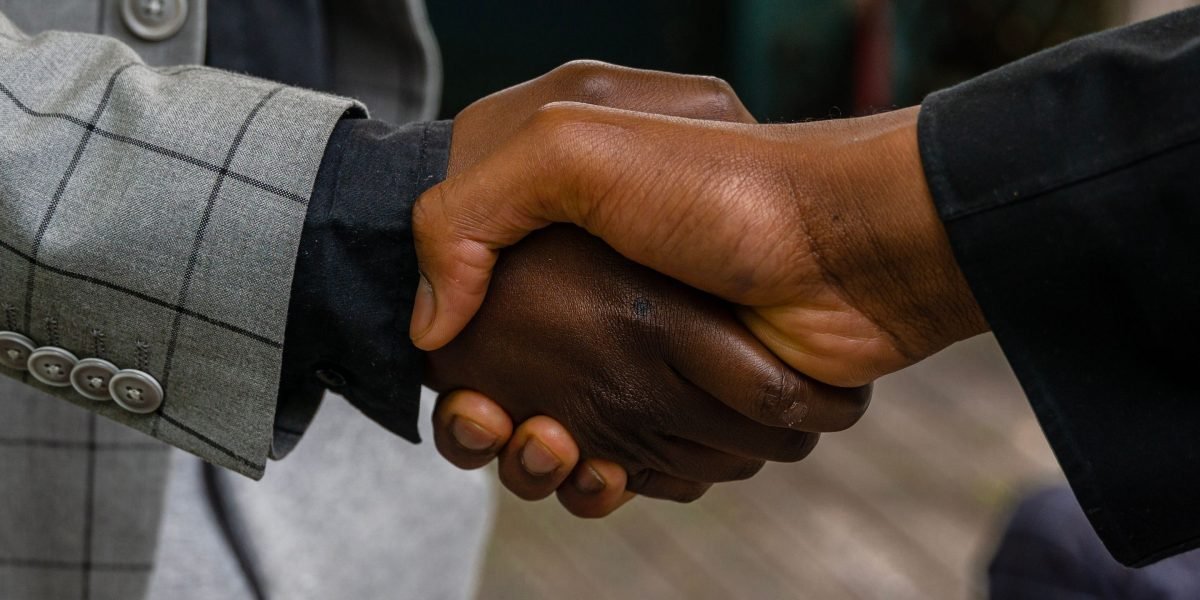 Two business professionals shaking hands in an office setting, symbolizing a successful partnership or funding agreement.