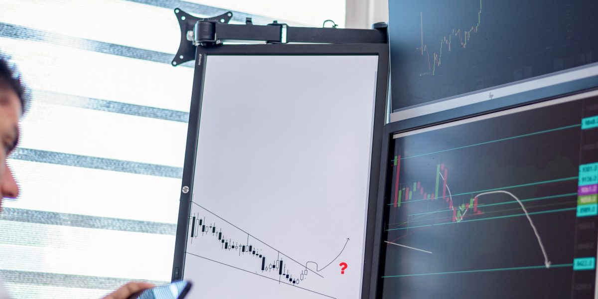 A professional intently analyzing financial market trends on a computer screen, symbolizing informed decision-making in a dynamic environment.