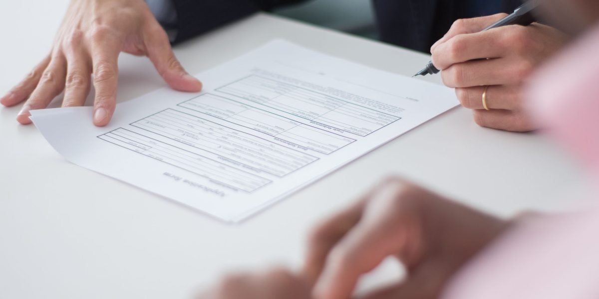 Two professionals engaged in a serious discussion, reviewing legal documents or a term sheet during a negotiation process.