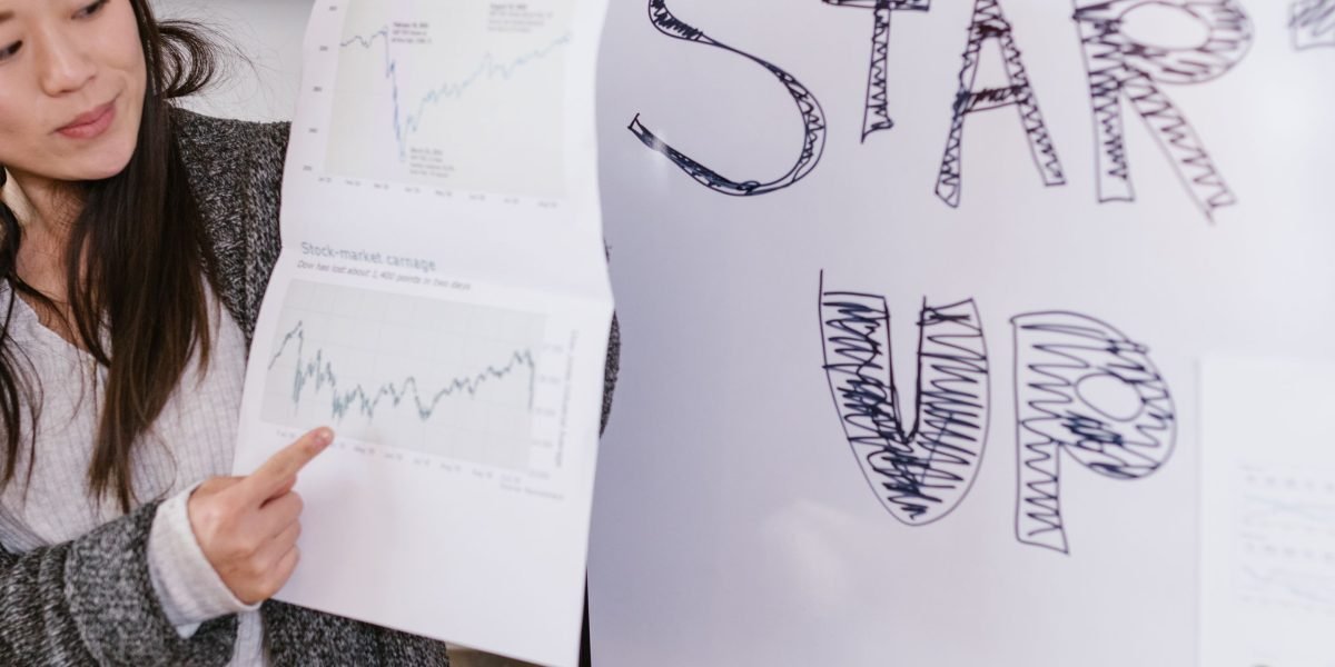 An entrepreneur confidently presenting their business idea on a whiteboard to an engaged audience of potential investors.