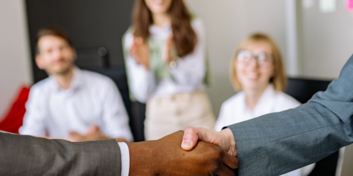 Business leaders shaking hands across a table, symbolizing the successful negotiation and closing of a deal.